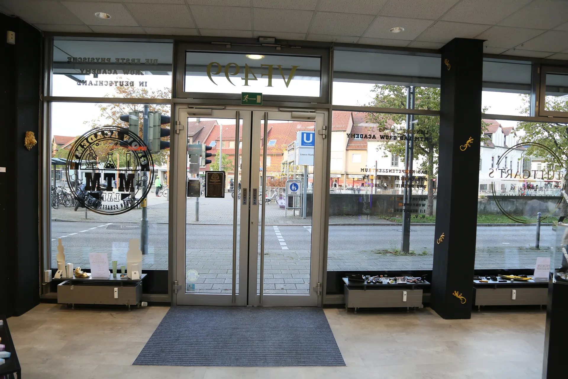 Blick von innen auf die Eingangstür und die Schaufenster, davor niedrige Fensterbänke mit ausgelegten Produkten
