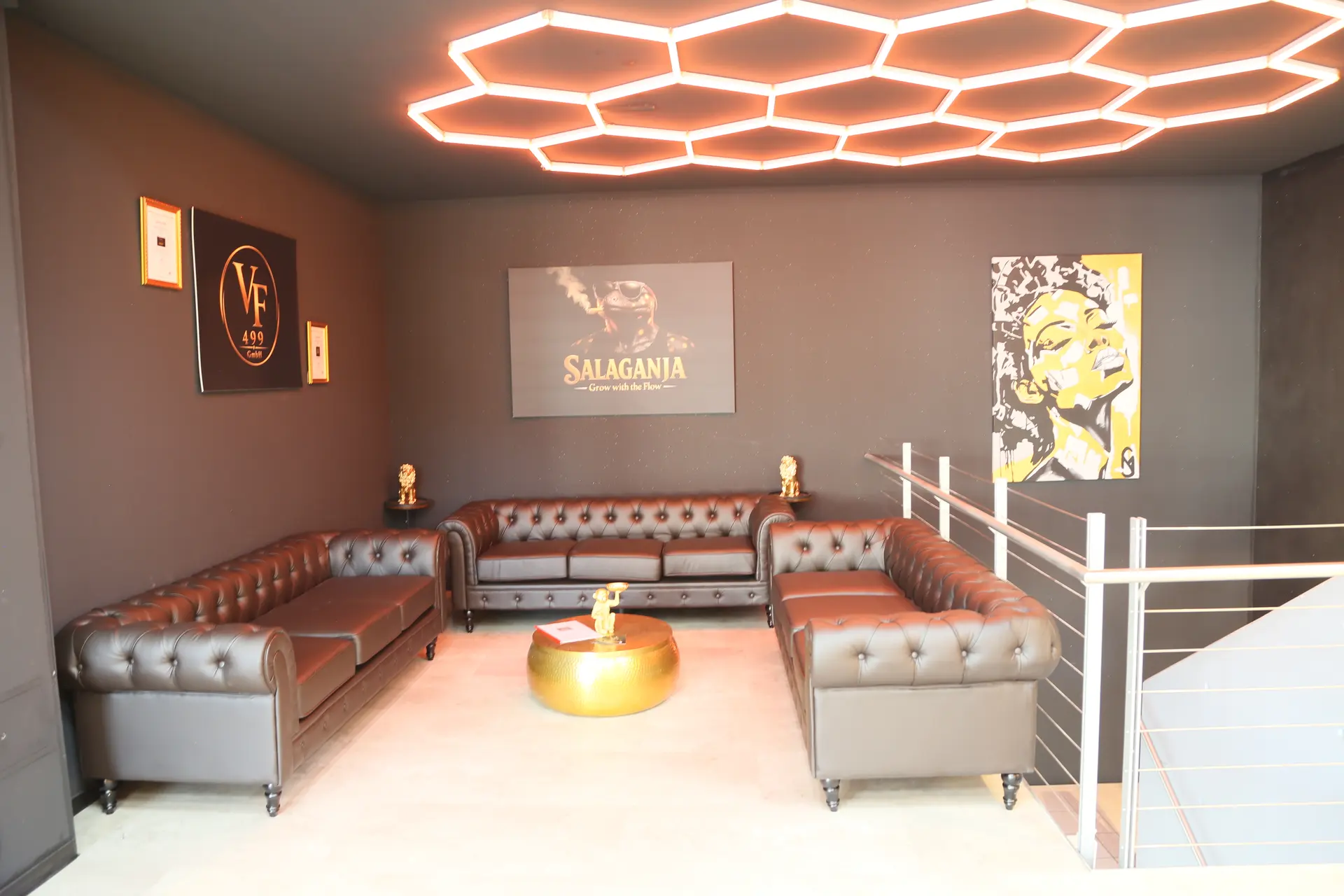 Die Lounge mit braunen Chesterfield-Sofas unter einer wabenförmigen Lichtdecke