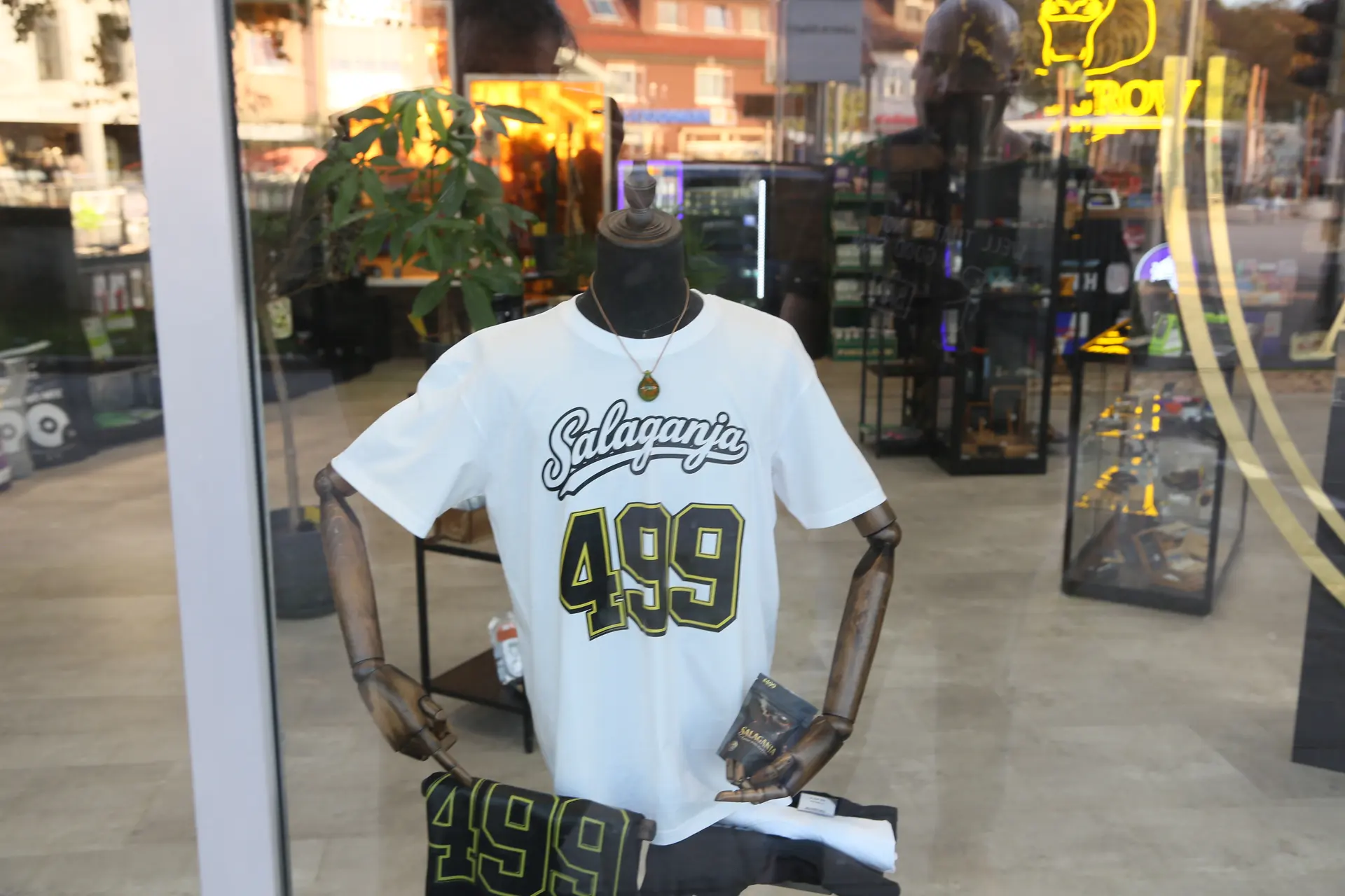 Schaufensterpuppe mit weißem Salaganja-T-Shirt mit der Nummer 499, dahinter der Laden
