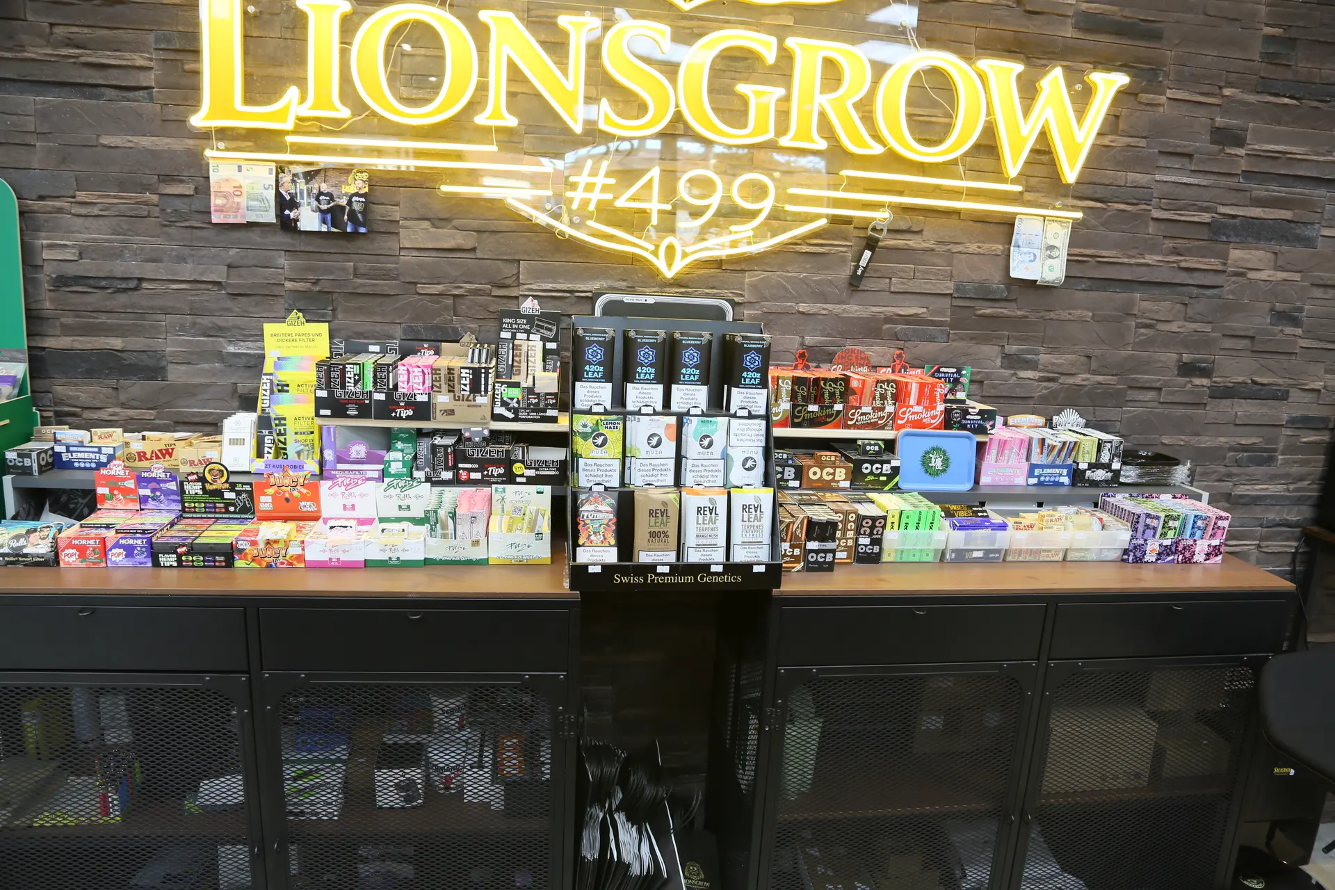 Nahaufnahme des Tresens mit vielen bunten Packungen Papers und Filter unter dem leuchtenden Lionsgrow-Schriftzug
